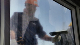 Nettoyage d'une fenêtre en hauteur par deux travailleurs à l'aide d'une nacelle